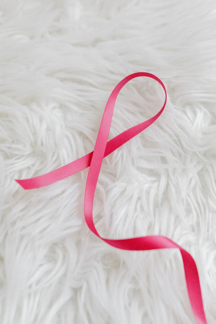 Elegant pink ribbon on a plush white furry surface for a delicate, soft look.